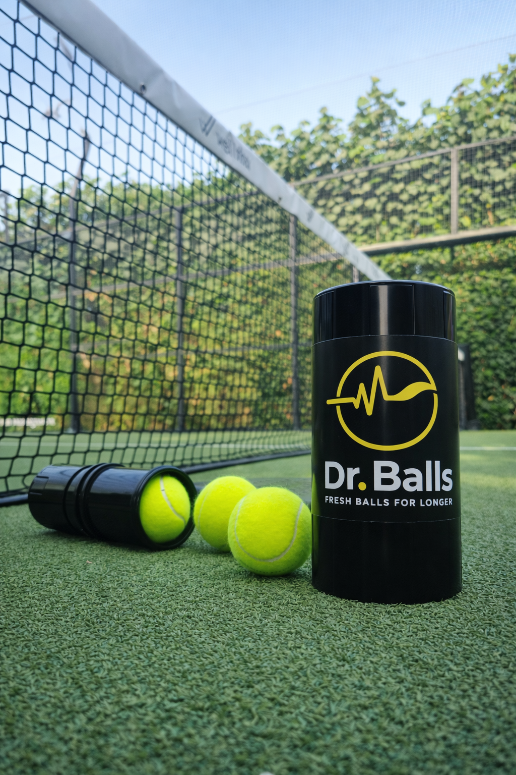 Dr. Balls smart tennis ball container on a tennis court with tennis balls